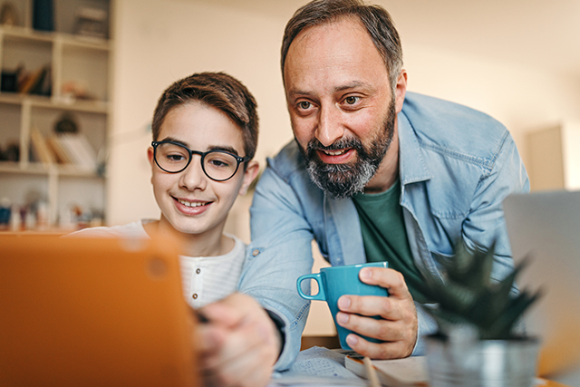 Man and boy using laptop for learning.