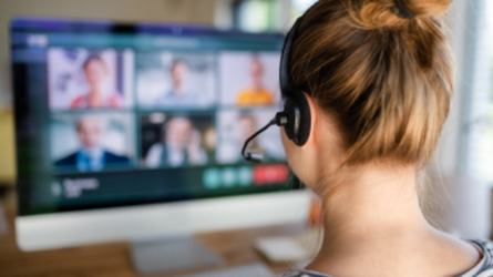 Person wearing headset attending online video meeting on desktop computer