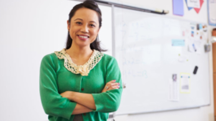 Smiling teacher standing in front of whiteboard in classroom